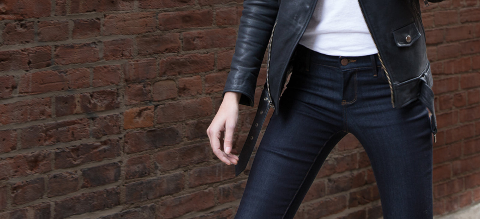 Woman in dark denim leaning on a railing, leather jacket, NYC street